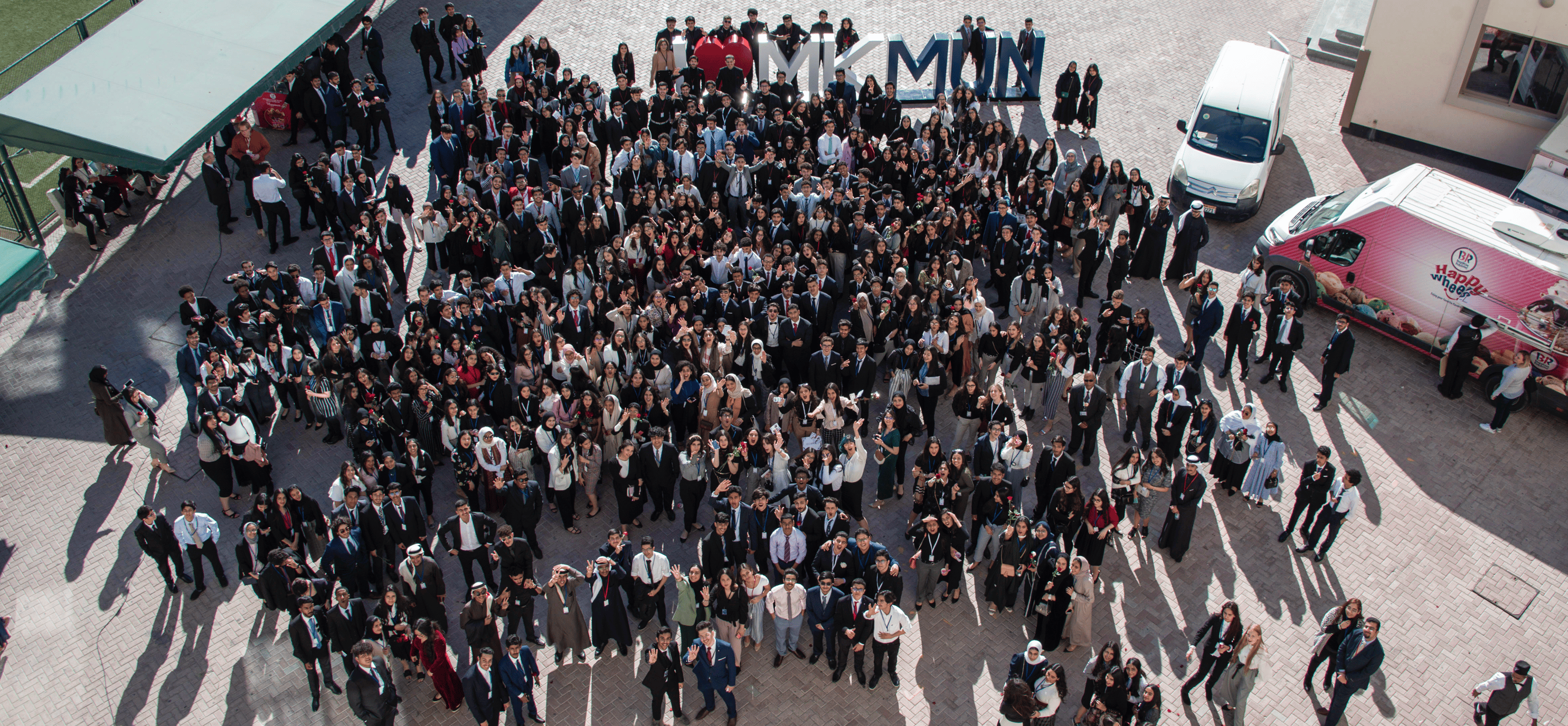 Students gathering outside MKS International School Bahrain during graduation event, showcasing diverse learners in formal attire.