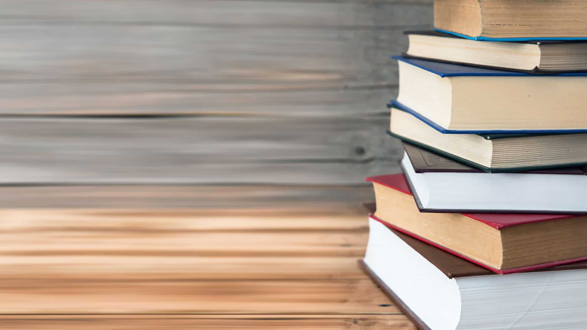 Colorful stack of books on wooden desk, university and academic study materials, learning and education concepts, typical school library or classroom supplies, preparing students for exams and research.