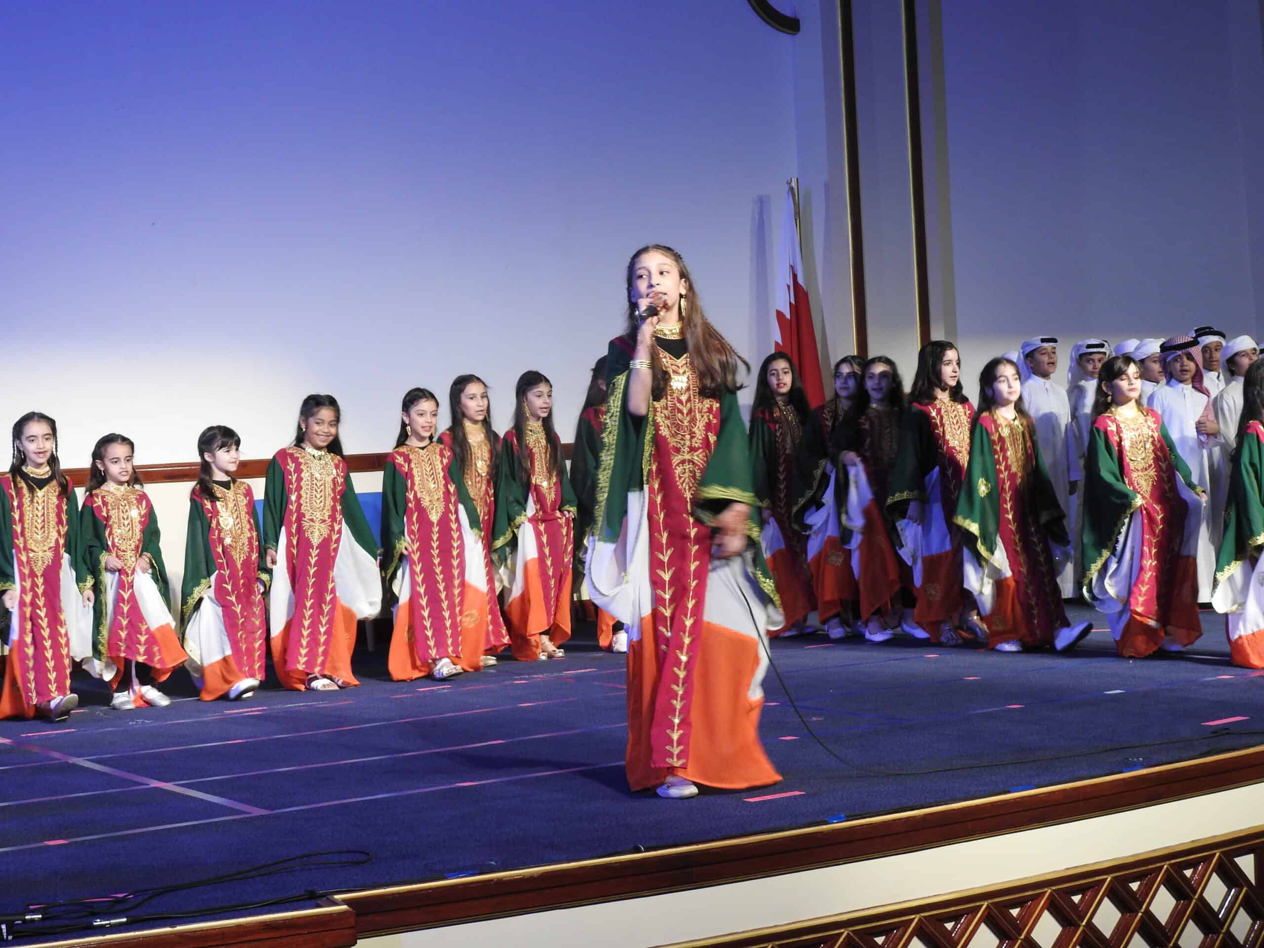 Children performing cultural dance on stage at MKS Bahrain, showcasing traditional attire and vibrant performances representing Bahraini heritage and cultural diversity.