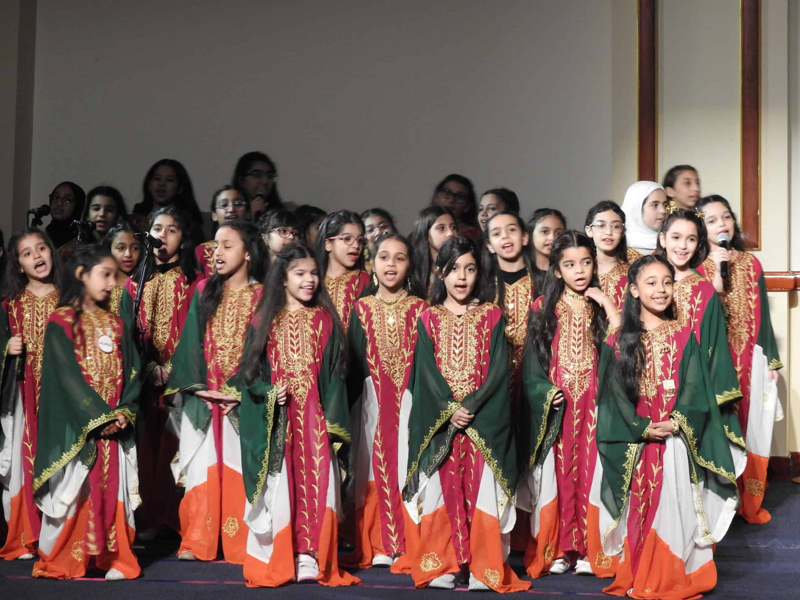 Children's choir performing on stage at MKS School event, showcasing cultural music and school spirit in traditional attire, emphasizing arts and education excellence.