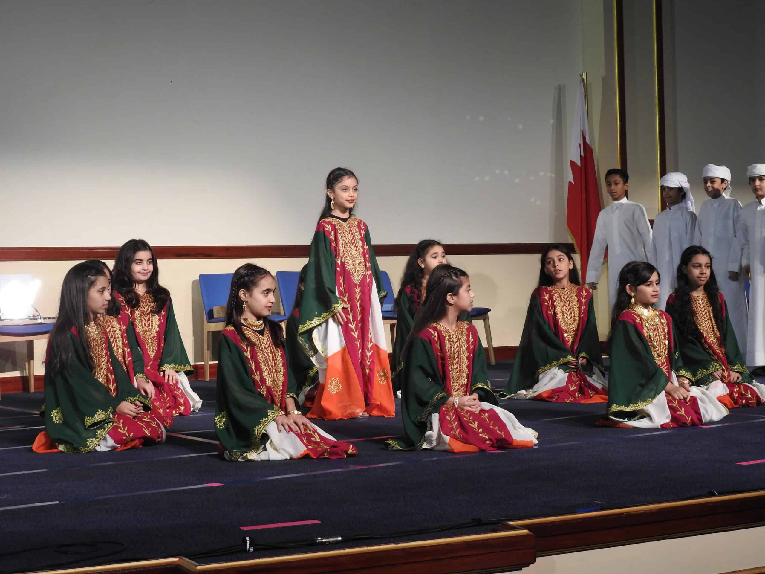 Girls in traditional attire performing on stage at MKS Bahrain, showcasing cultural heritage and school activities.