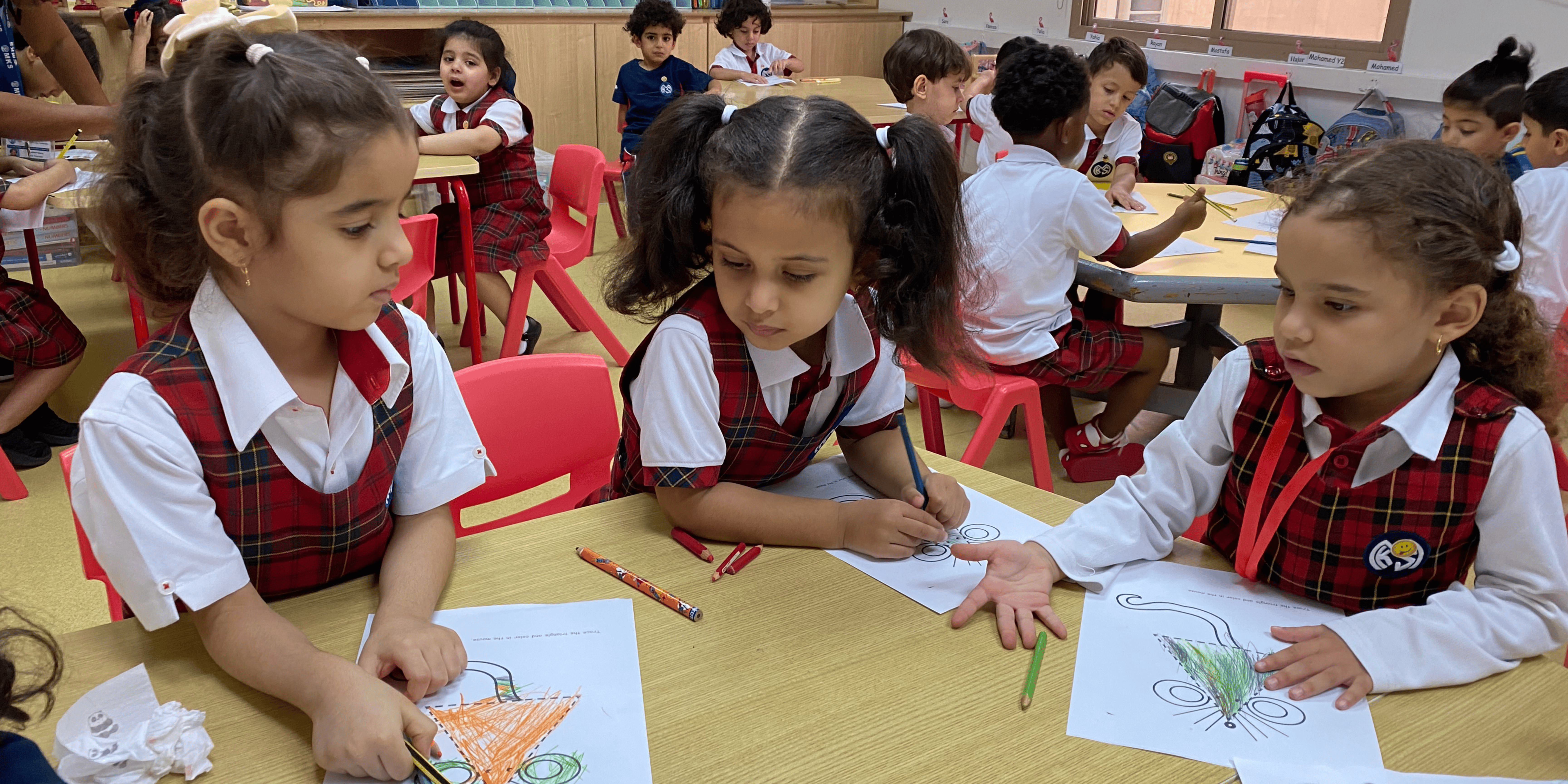 Blue and white school uniforms for young students studying in classroom at MKS school.